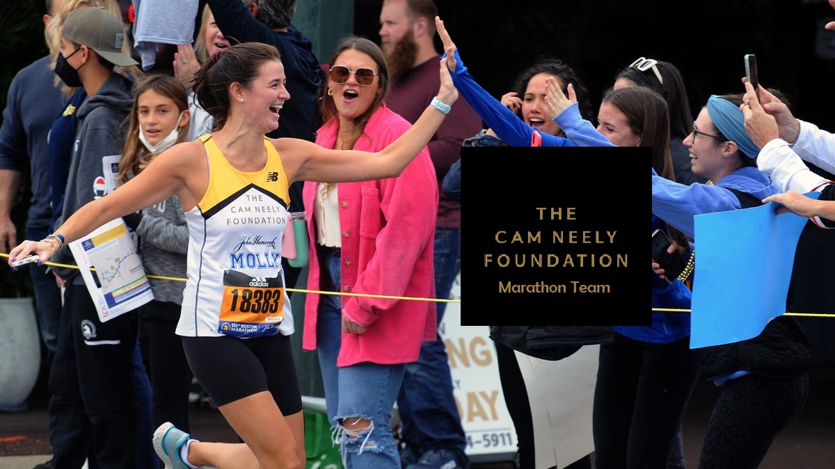 Female marathoner high fiving spectator. She is wearing a Cam Neely Foundation singlet